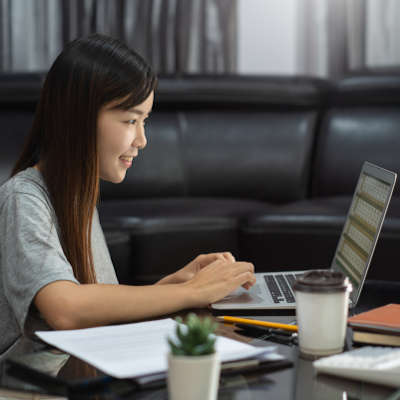 Attractive young beautiful asian woman Entrepreneur or freelancer working at home with laptop business reports and online communications on living room sofa, working remotely access concept.